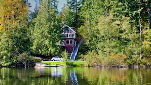A house on stilts over a lake, surrounded by dense forest.
