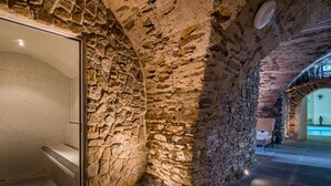 A stone-walled bathroom with a tiled shower area and a bench. - Schlosshotel Purschenstein (Neuhausen)