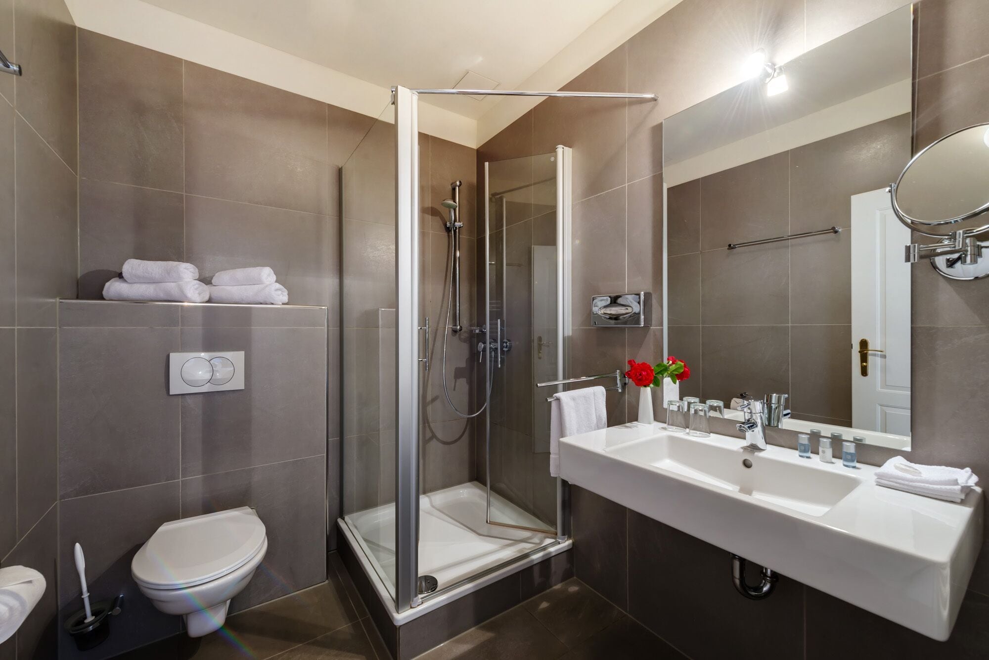 A modern bathroom with a glass-enclosed shower, a white sink, and a toilet.