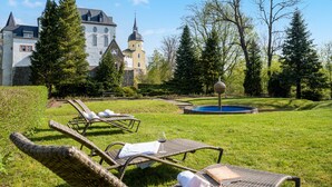A courtyard with lounge chairs, a swimming pool, and a large building with towers. - Schlosshotel Purschenstein (Neuhausen)