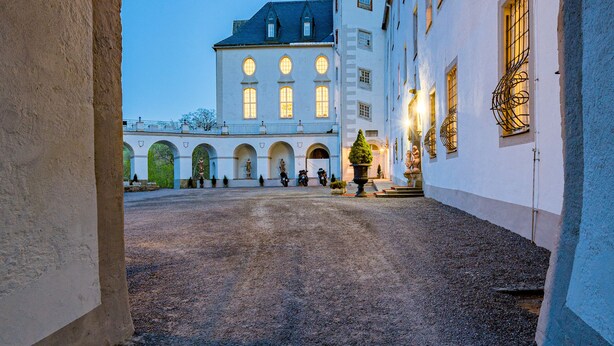An arched corridor leading to a building with a tower and a courtyard. - Schlosshotel Purschenstein (Neuhausen)