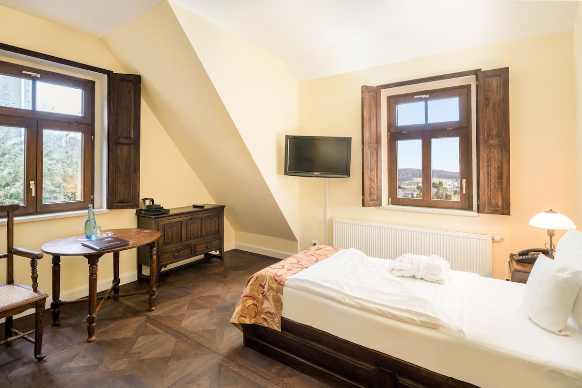 Een hotelkamer met een bed, een bureau, een stoel, een televisie en een raam met uitzicht.