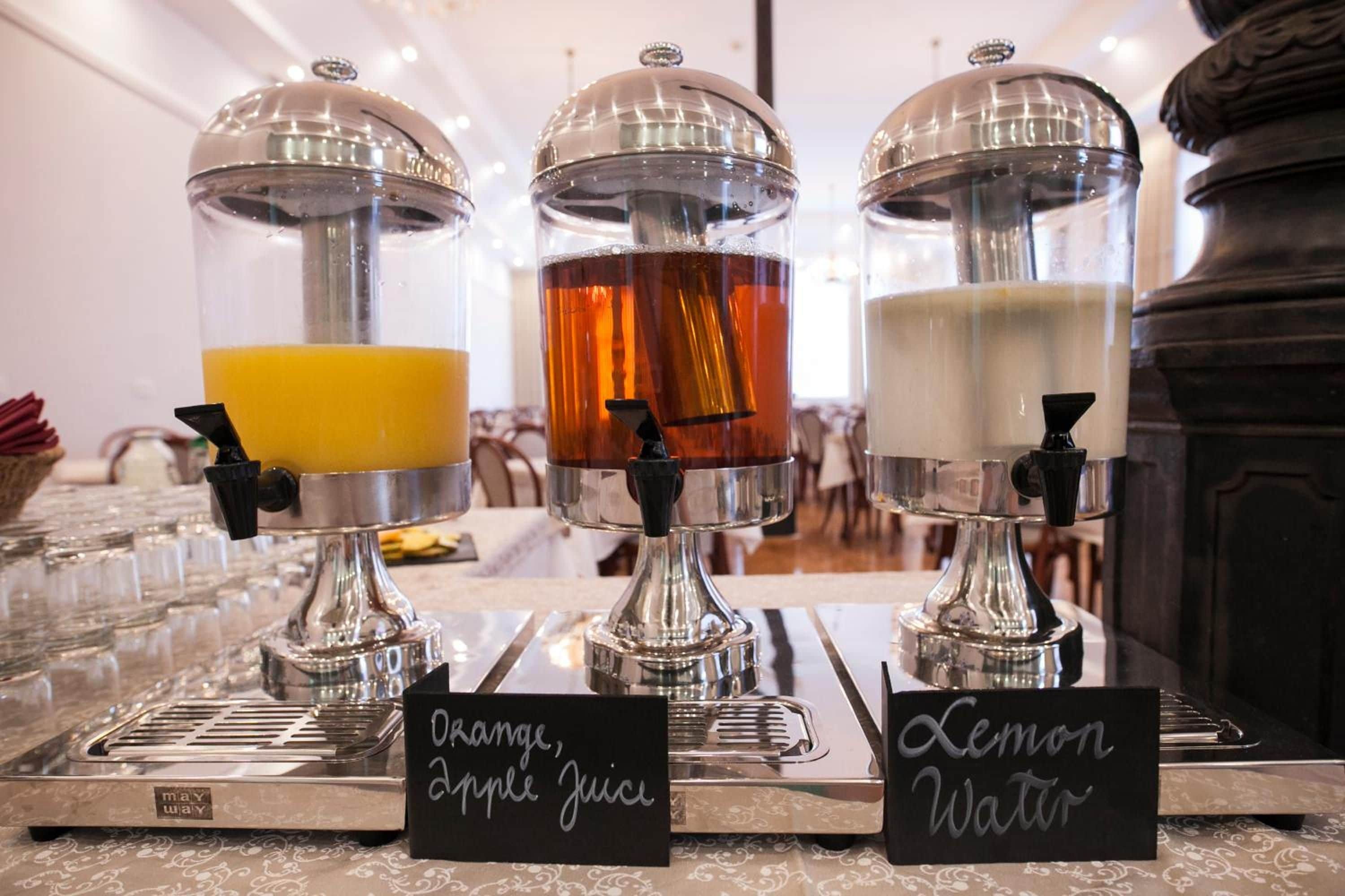 A beverage station with dispensers for orange, apple juice, and lemon water.