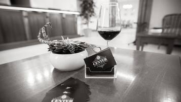 A hotel reception area with a glass of red wine, a decorative plant, and a Center Hotel brochure on a wooden table.