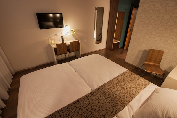 Habitación de hotel con una cama grande, un escritorio con silla, televisor montado en la pared y un espejo.