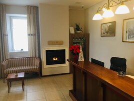Una sala de estar con chimenea, un sofá a rayas, una mesa de centro de madera, un mostrador de recepción y una planta en maceta.