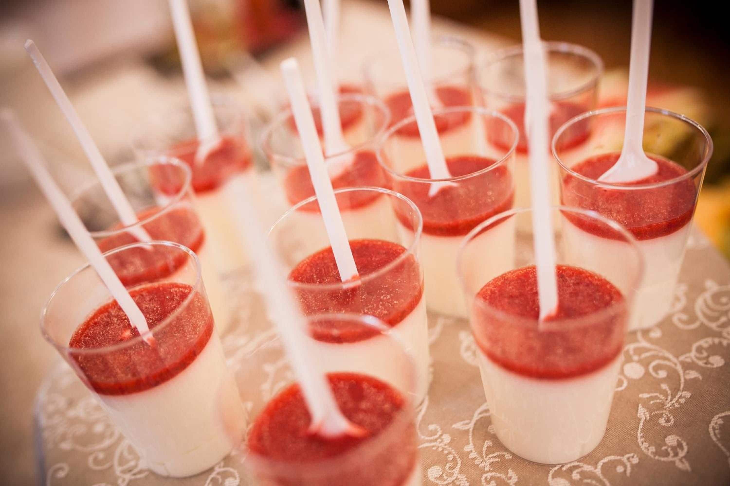 Flere glas med hvide sugerør, fyldt med en lagdelt dessert.