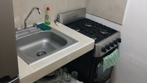 Uma cozinha compacta com pia, fogão e bancada pequena.