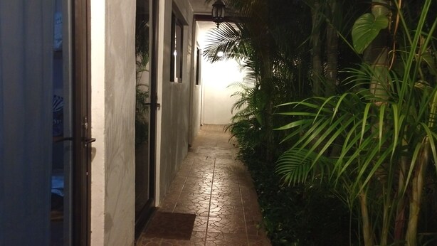 Um corredor estreito com chão e paredes em azulejo, que leva a uma porta.