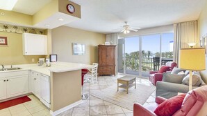 A hotel room with a kitchen, dining area, and a balcony with a view.