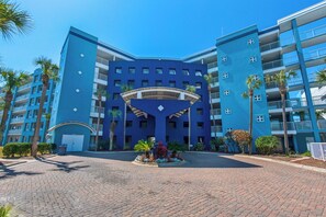 Un hôtel à plusieurs étages, doté d’une façade bleue, d’une cour intérieure et de palmiers.
