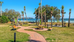 A park with picnic tables, benches, and a paved walkway.