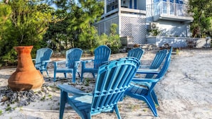 Une propriété située en bord de mer, dotée d’un espace extérieur aménagé avec des sièges, d’un grand pot en terre cuite et d’une maison aux accents bleus et agrémentée d’un balcon.