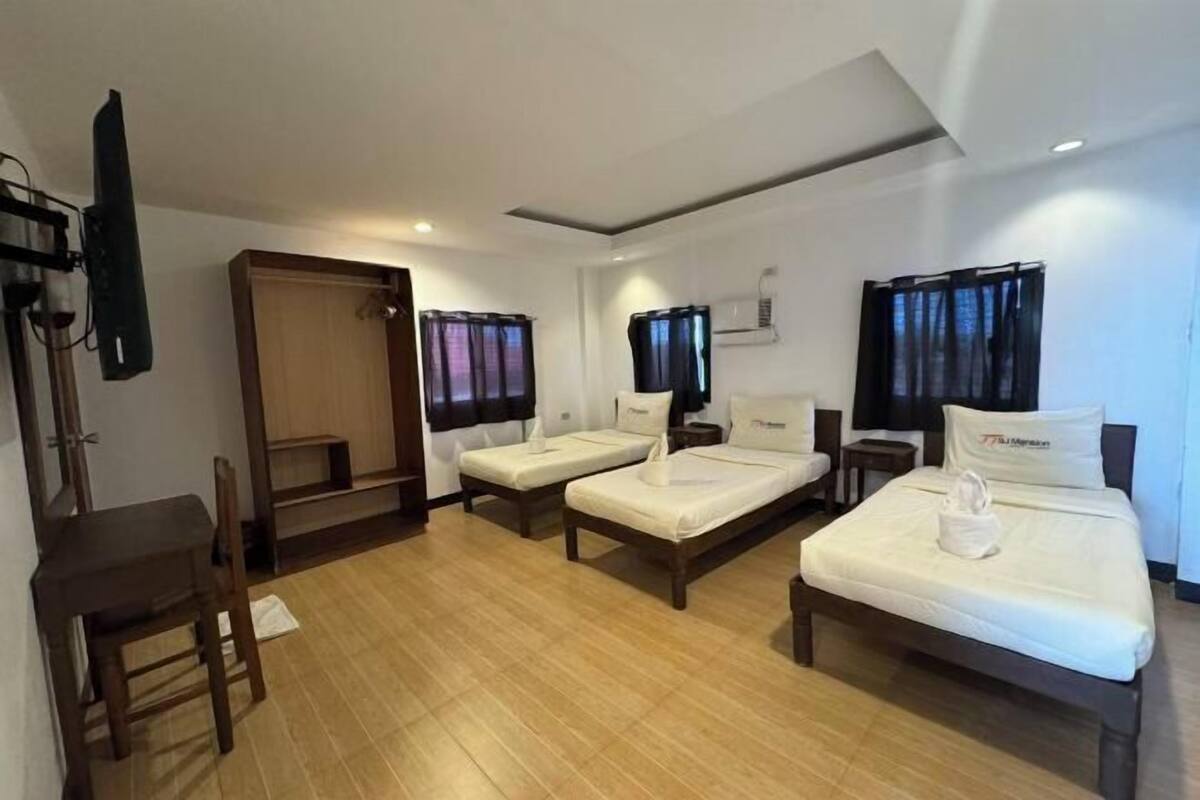 A hotel room with two single beds, a desk, a chair, a TV, and a wardrobe.