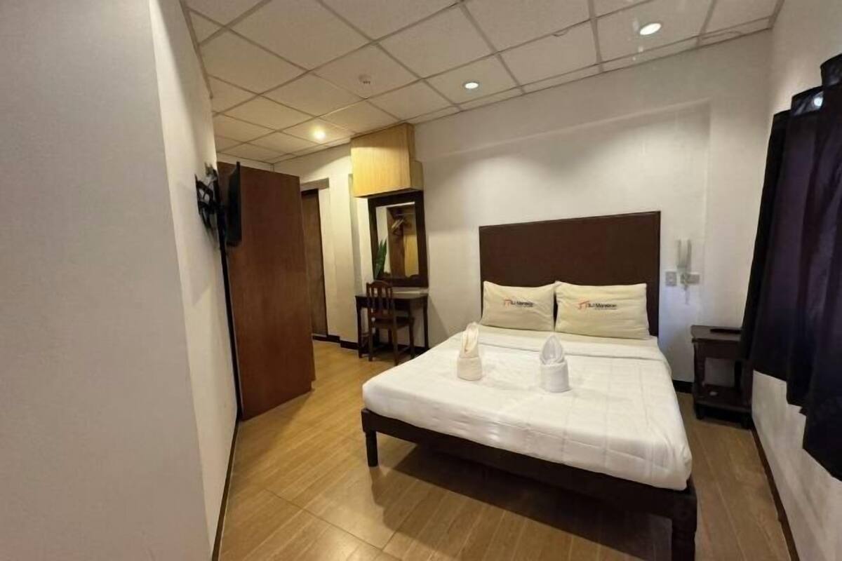 A hotel room with a bed, a desk, and a chair.