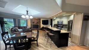A spacious living area with a stone fireplace, a dining table with chairs, and a kitchen with modern appliances. - Monkey Island Waterfront with Dock and boat ramp right next to it. (Afton)