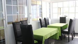 A dining area with black leather chairs and tables covered with green tablecloths. -  Crystalem Luxury Hotel (Uyo)