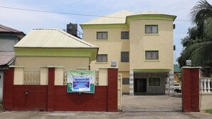 A two-story building with a gated entrance, a banner, and a clear sky. -  Crystalem Luxury Hotel (Uyo)