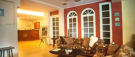A living room with a sofa, coffee table, and a painting on easel.