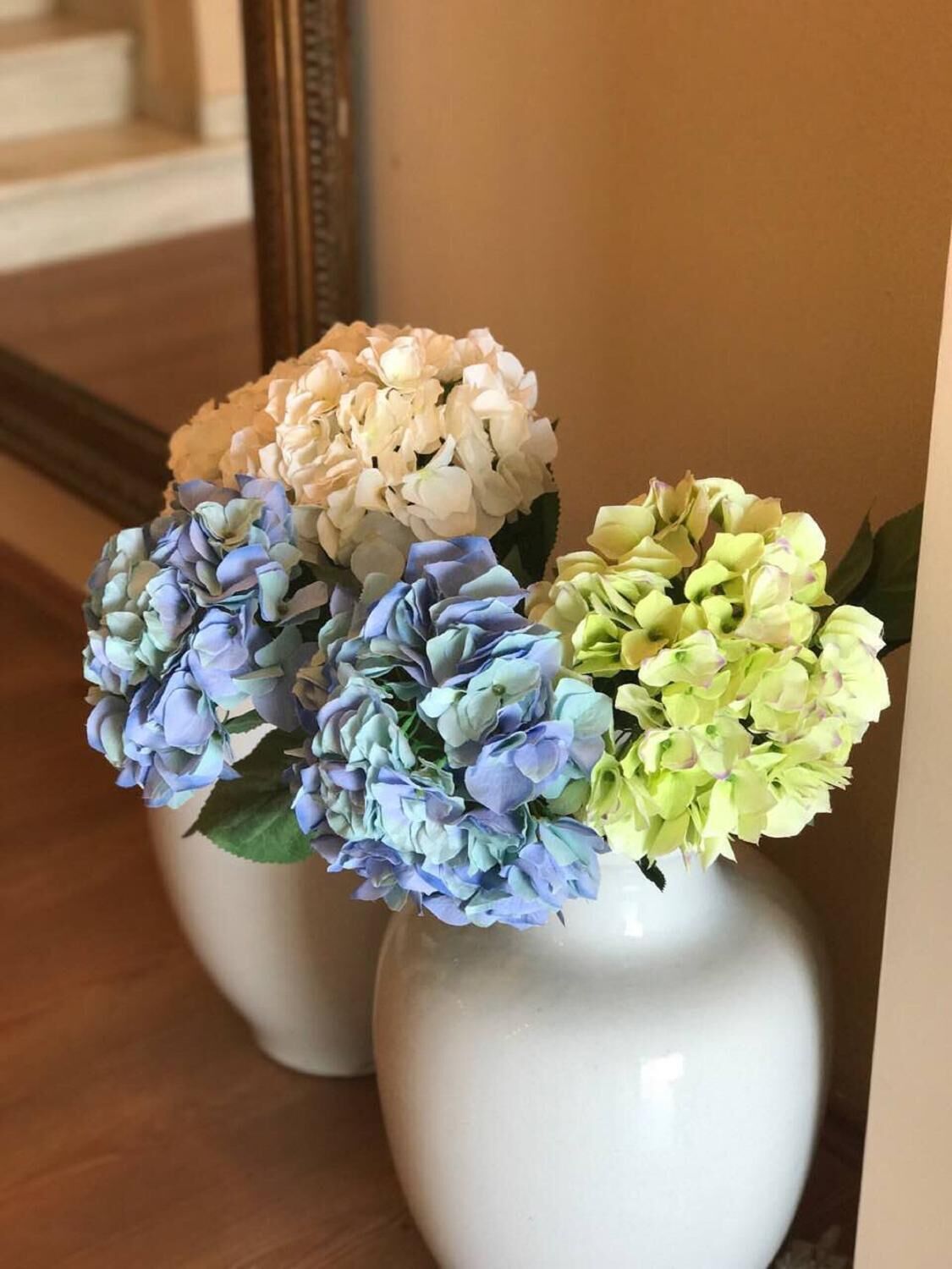 Three white vases with hydrangea flowers in pastel colors.