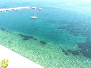 A marina with clear turquoise water and a dock extending into the sea. - Hotel Methanion (Troizinia)