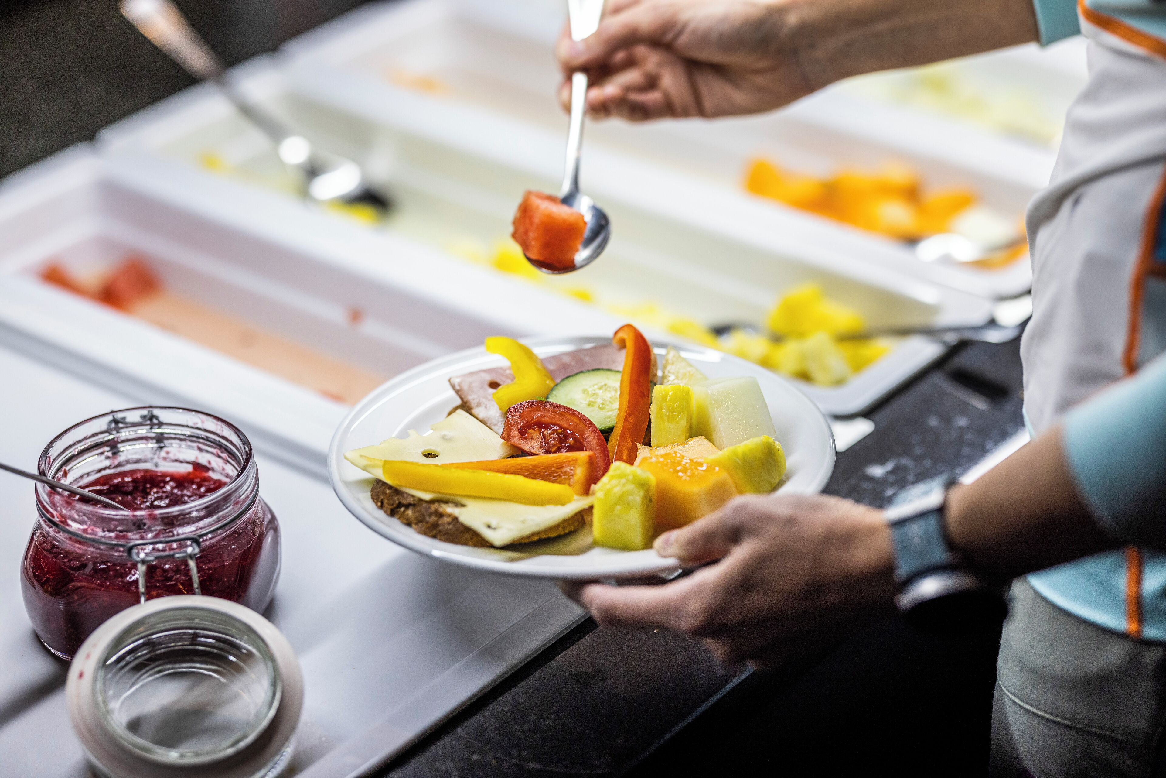 Una mesa de buffet con diversos alimentos y un tarro de mermelada.
