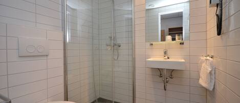 A modern bathroom with a glass-enclosed shower, a white sink, and a toilet.