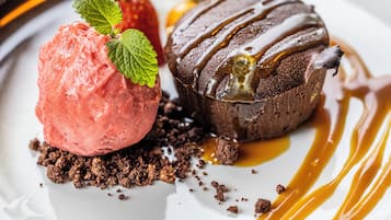 Een nagerechtenbord met een bol aardbeiensorbet en een chocolade lava cake, beide overgoten met karamelsaus.
