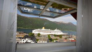 Un crucero amarrado en un puerto con montañas al fondo y edificios residenciales cerca.