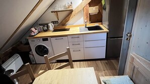 Pieni, käytännöllinen keittiö, jossa on pyykinpesukone, pesuallas ja jääkaappi.