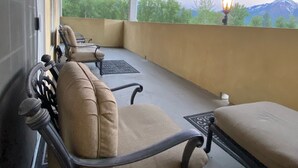Un balcón cubierto con techo de madera, una banca y una mesa.