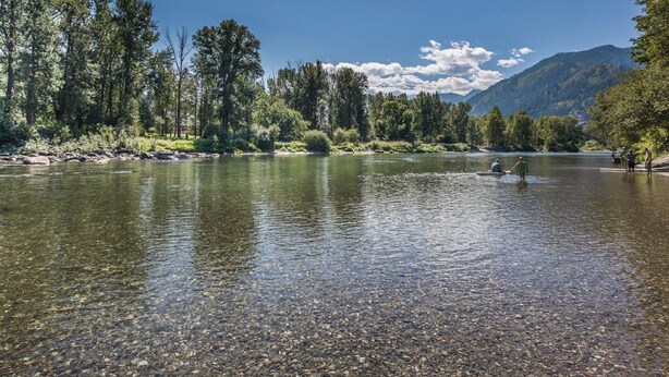 Un río de aguas cristalinas, rodeado de árboles y montañas.