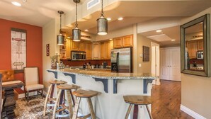 Una cocina con armarios de madera, electrodomésticos de acero inoxidable y una isla central con taburetes.