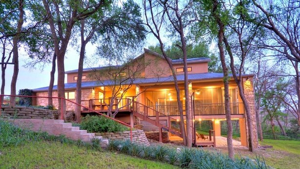A modern house with a stone facade, a wooden deck, and a staircase leading to a balcony. - Spacious Riverfront Home (Martindale)