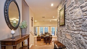 A hallway with a wooden bench, a large mirror, and a stone wall. - Spacious Riverfront Home (Martindale)