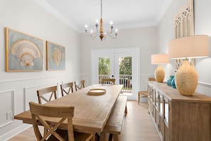Ein Esszimmer mit Holztisch, Stühlen, einer Chandelierleuchtre und Kunstwerken an den Wänden.