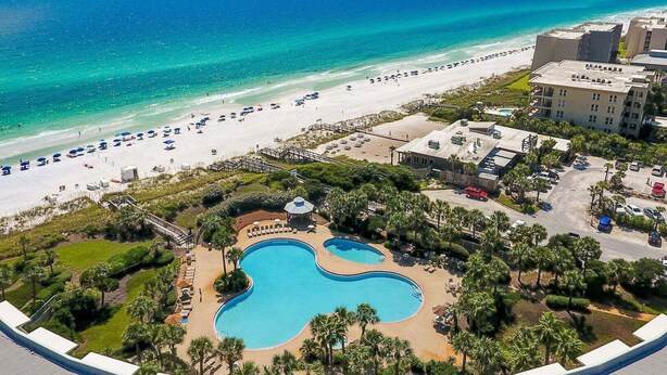 A resort with a beach, a pool, and a parking area.