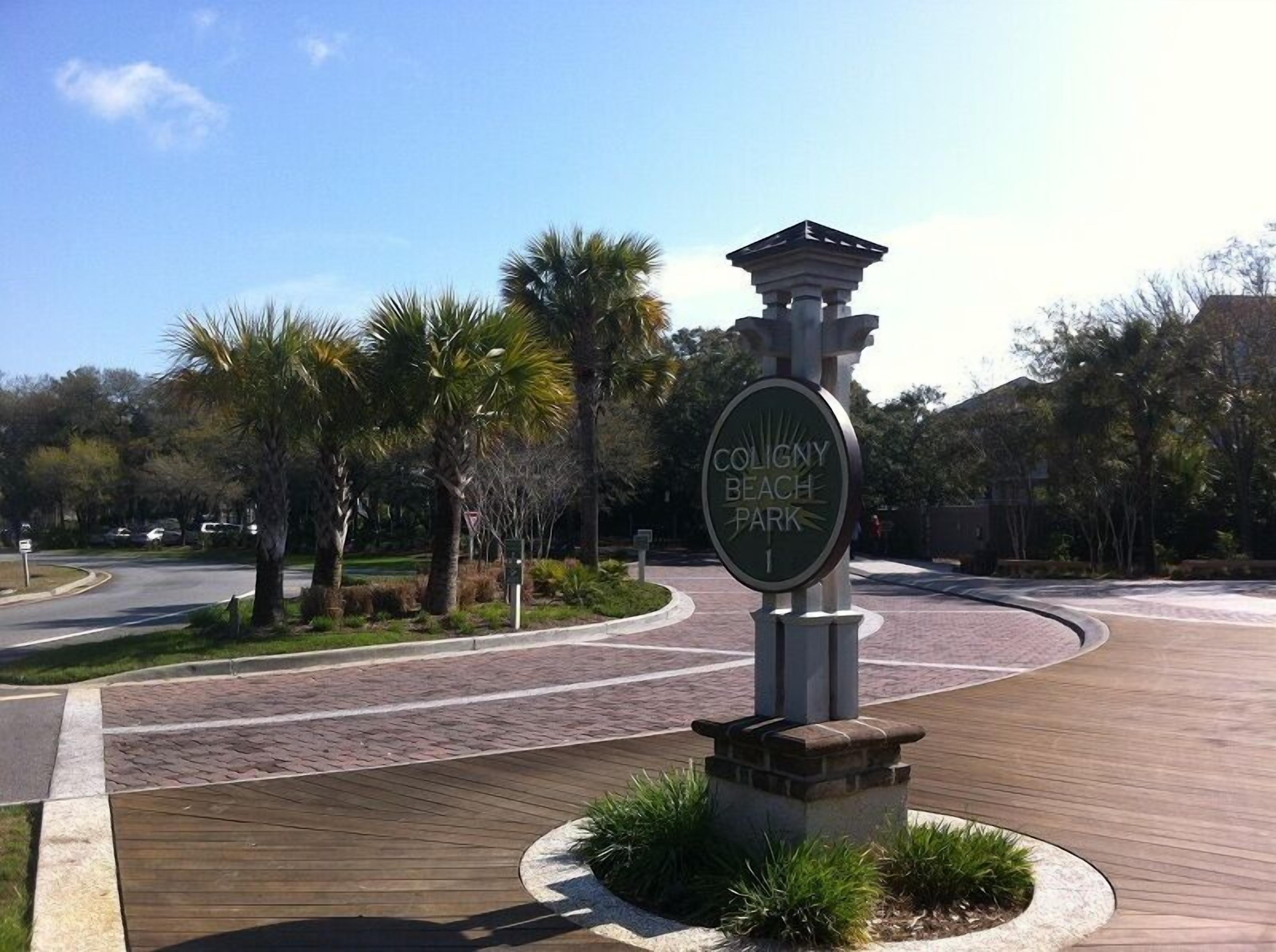 Schild für den Coligny Beach Park mit Grünflächen und Palmen.
