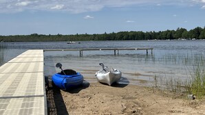 A calm lake with kayaks and a dock extending into the water. - Peaceful Retreat for Families/Couples/Groups - All Sports Lake w/ Kayaks & SUP's (Cadillac)
