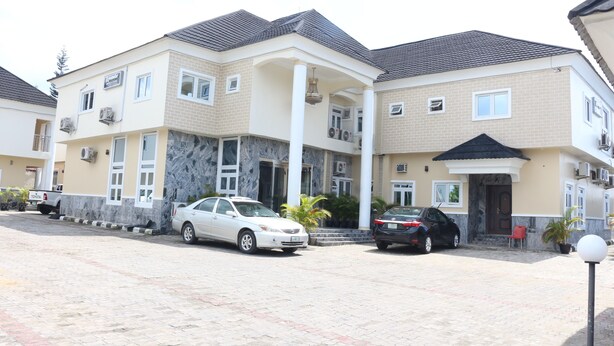 A multi-story residential building with a tiled roof, a covered entrance, and a paved driveway.