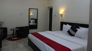 A hotel room with a bed, a small table, a chair, a mirror, and two wall-mounted lights.