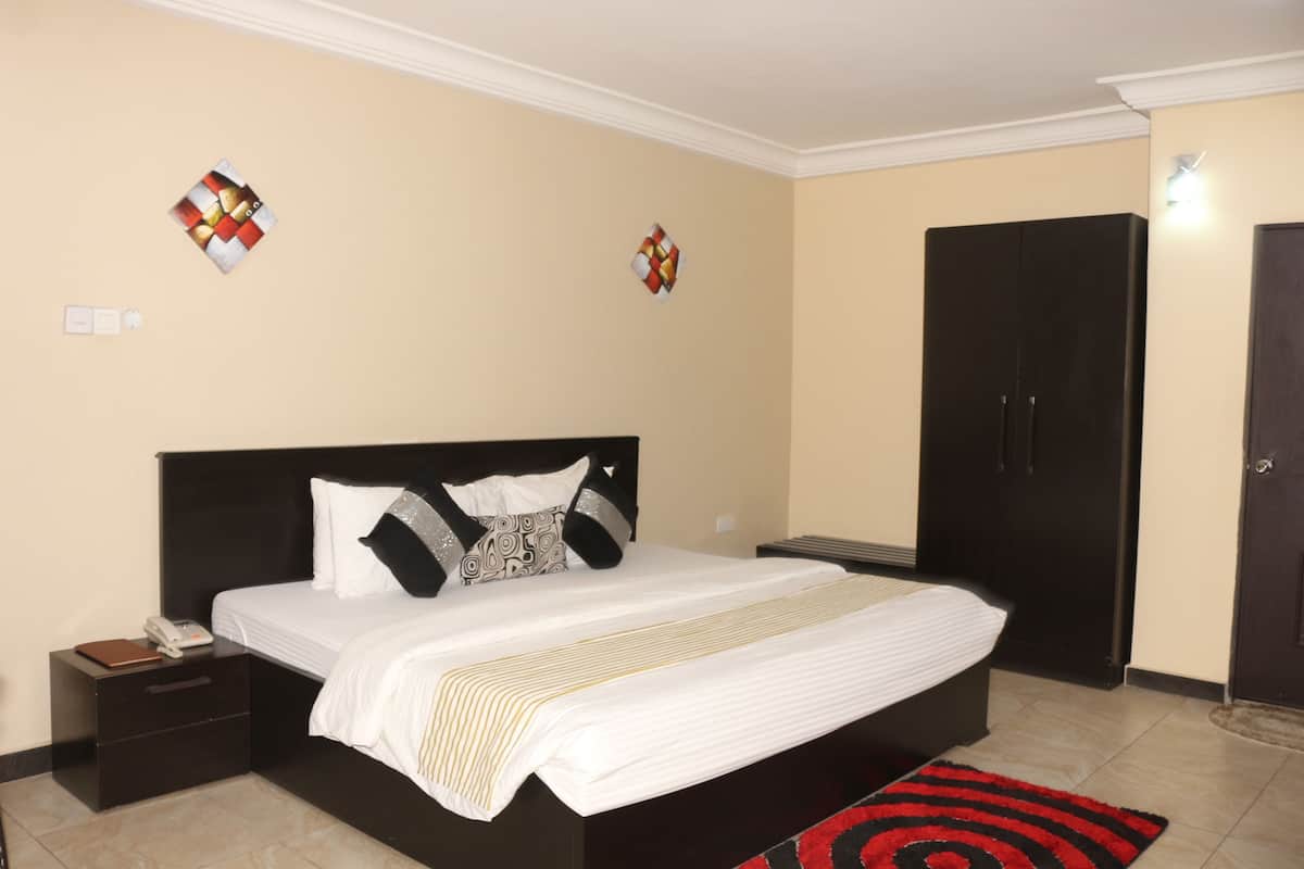 A neatly arranged bedroom with a bed, bedside tables, and a wardrobe.