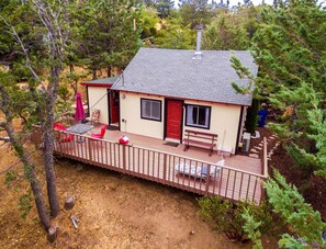 A small cabin with a deck, a red door, and a chimney. - 2 B/R Most Popular! "Time Traveler Retreat" (Pets Welcome) (Julian)