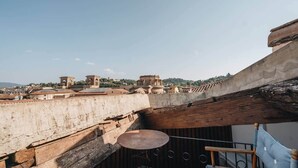 Eine Dachterrasse mit Blick auf historische Gebäude, einem runden Tisch und einem Stuhl.