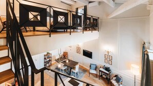 Ein mehrgeschossiges Interieur mit Treppe, Essbereich und einer Sitzecke mit Fernseher.