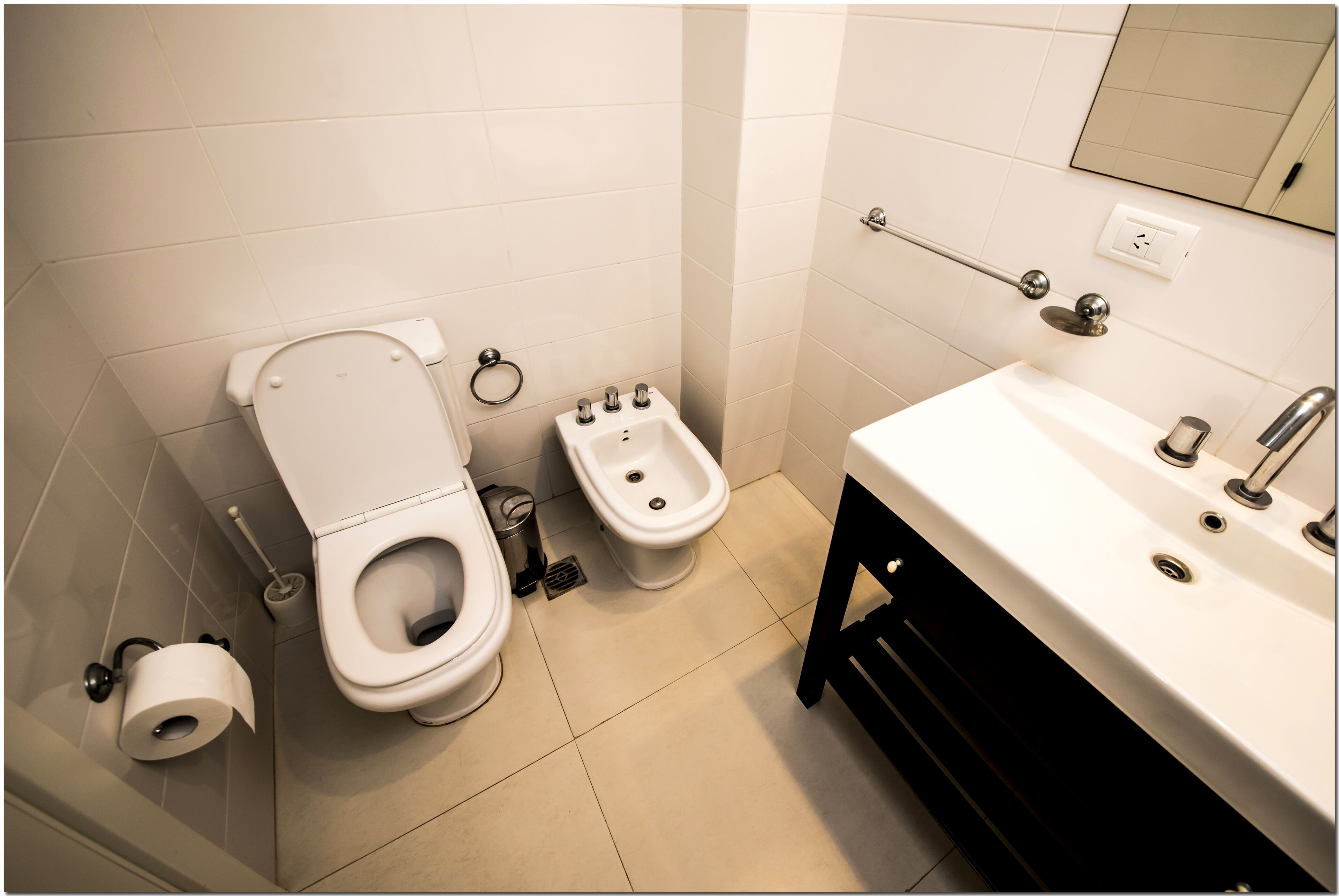 Un bagno con WC, bidet, lavandino e specchio.