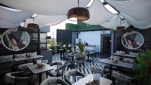 An outdoor seating area with tables and chairs, a patterned floor, and hanging pendant lights. - HOTEL SRR GRAND (Chennai)