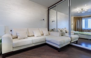 Relax in comfort with a large L-shaped sofa and a spacious mirror reflecting the room's interior.