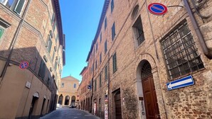 Una calle estrecha bordeada de edificios históricos, con una señal de no estacionamiento, una señal de dirección y un paso de peatones.