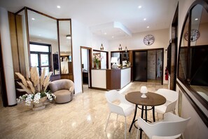 Recepció d'un hotel modern, amb escriptori, zona de seients i grans miralls.